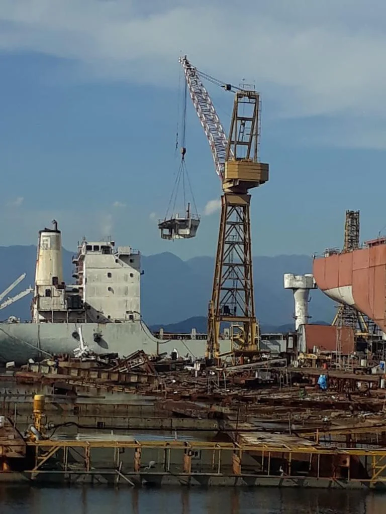 Operação industrial em estaleiro com guindaste e embarcações